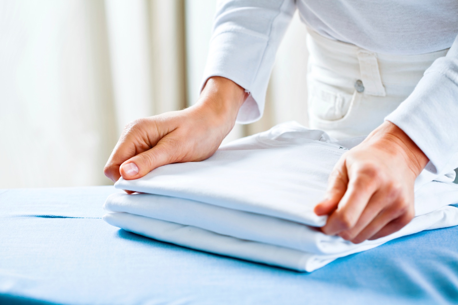 A crisp white shirt pressed flat and folded on a fresh pressing board